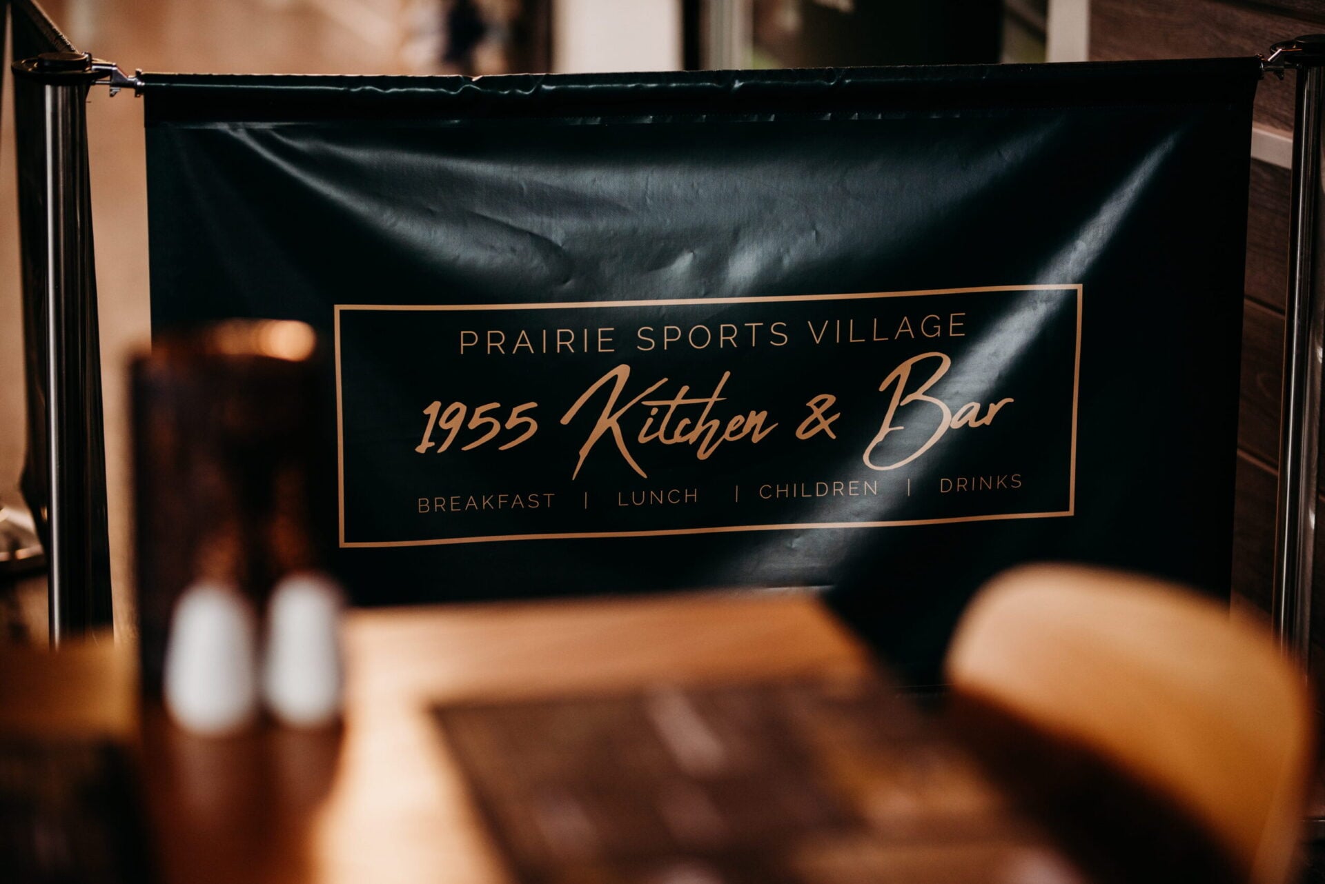 Signage for 1955 Kitchen & Bar displayed on a dark background.
