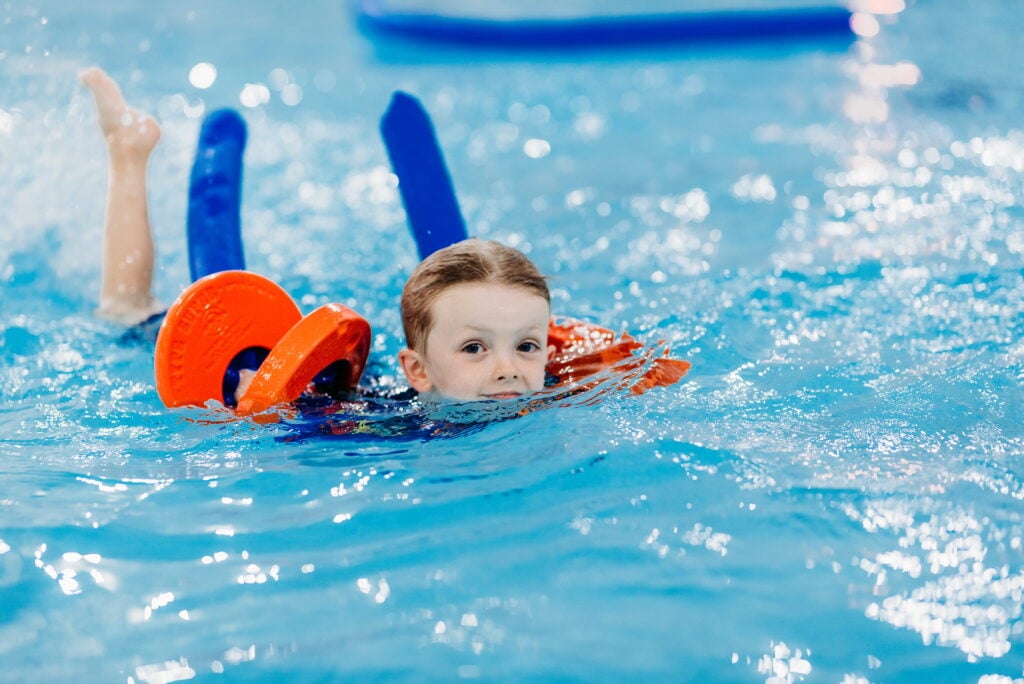 Children swimming with a pool noodle