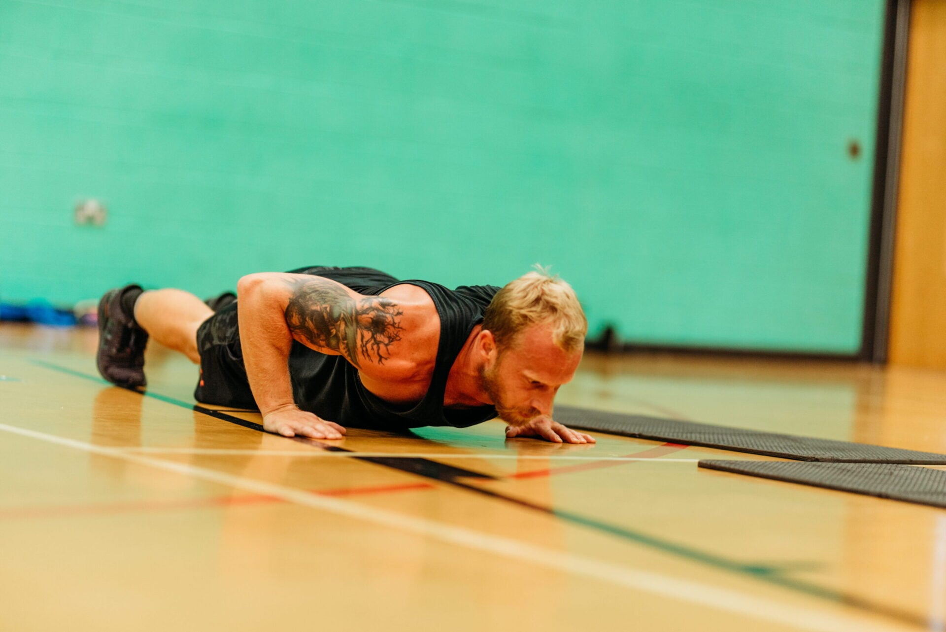 A man performs a push-up during a fitness class on a mat.