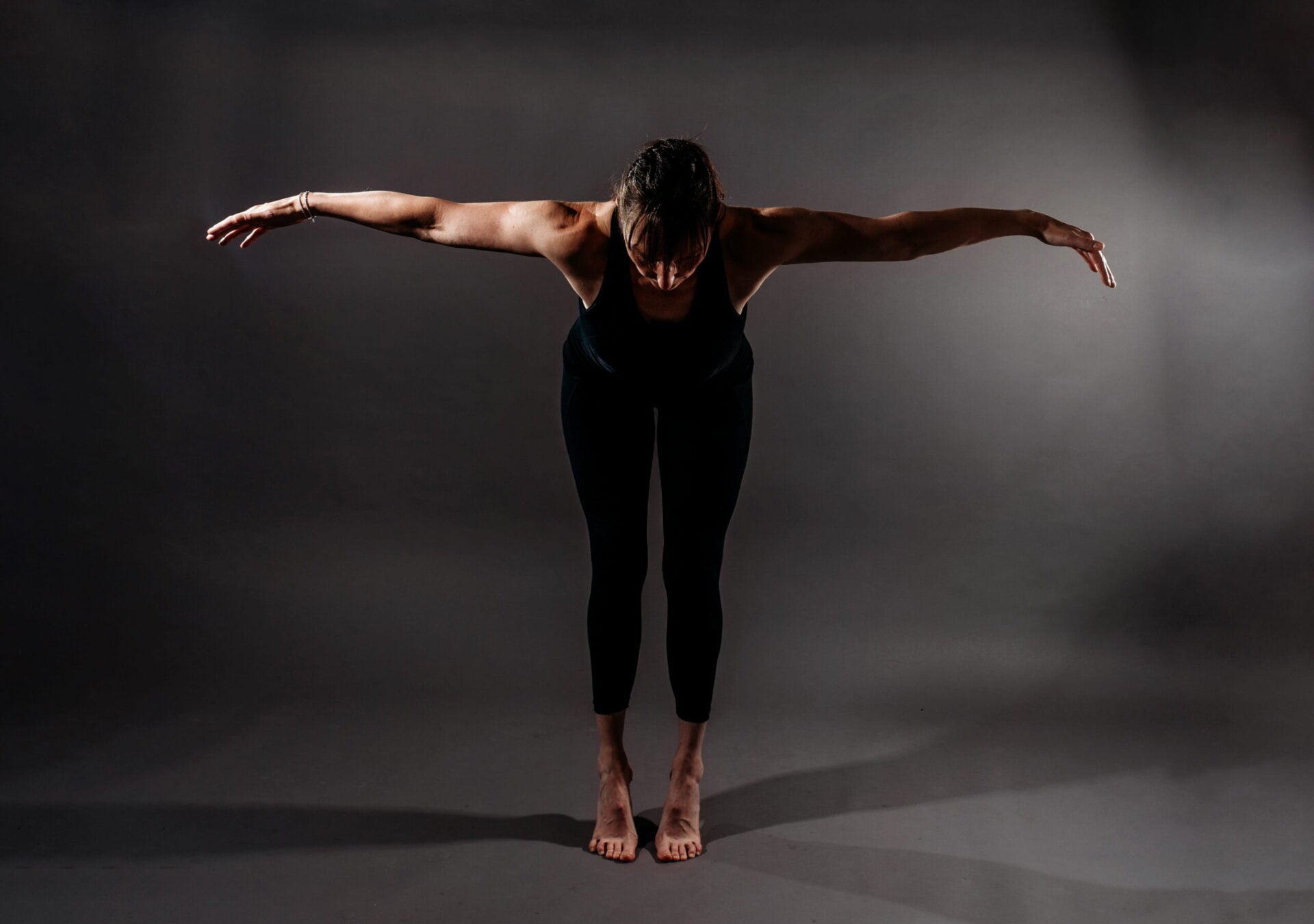 A woman performs a stretch with arms extended during a dance or fitness session.