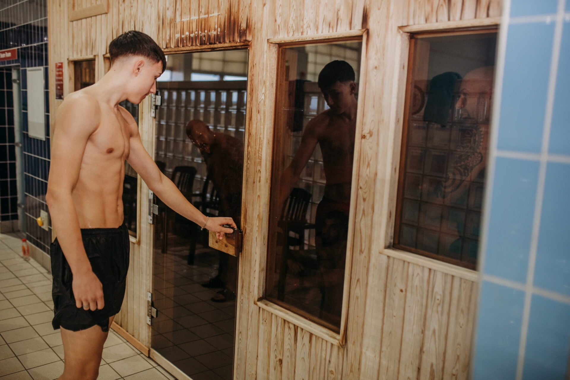 Young man opening the door to the sauna