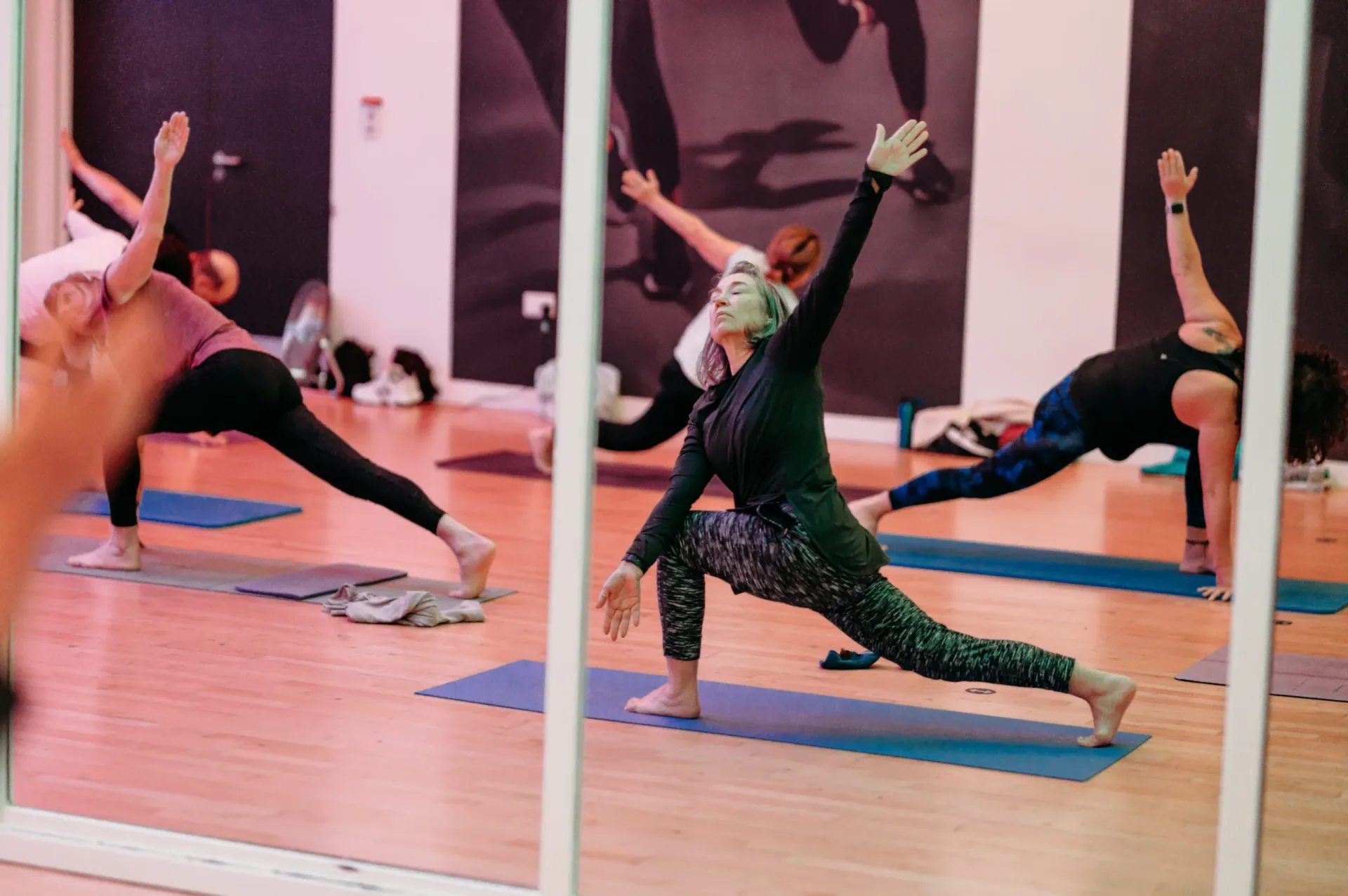 A group yoga session captures participants stretching into triangle pose on mats in a studio